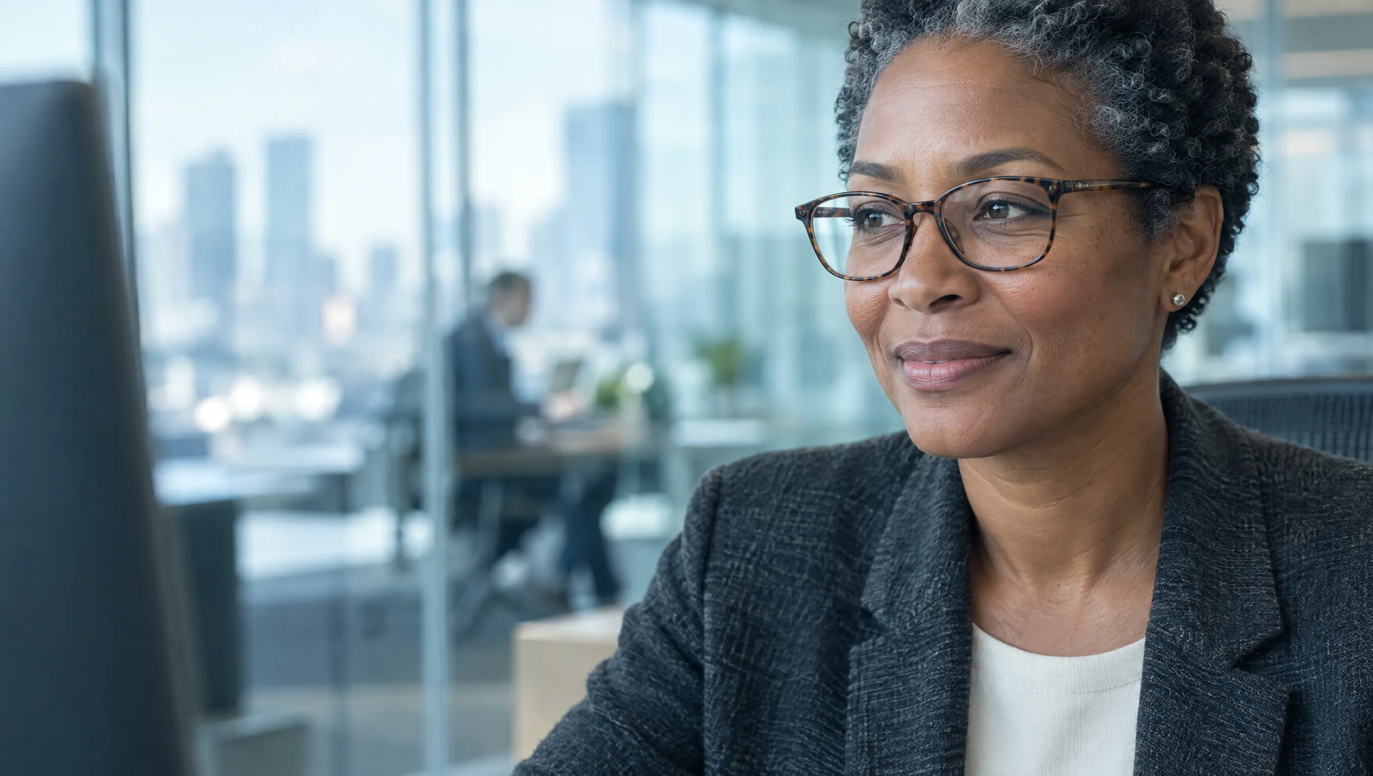 A finance executive at her desk, looking at a monitor
